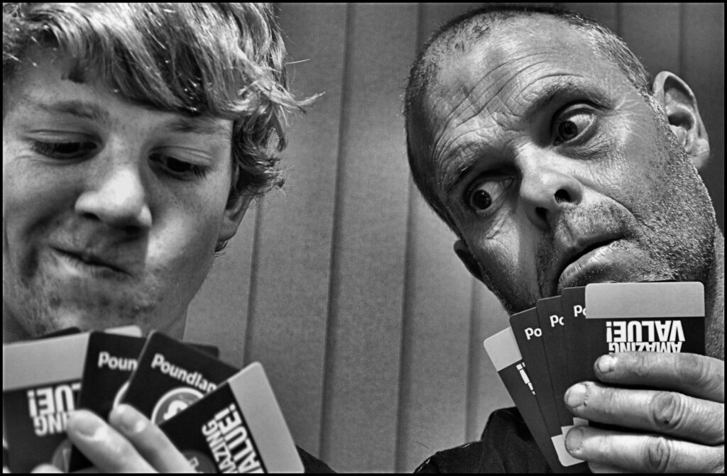 Two players holding cards, one of whom is cheating by looking at the others' cards