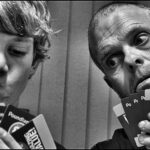 Two players holding cards, one of whom is cheating by looking at the others' cards